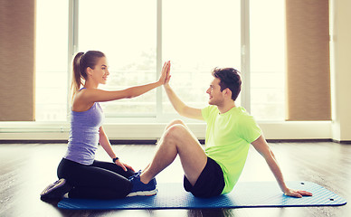 Image showing man with personal trainer doing sit ups in gym