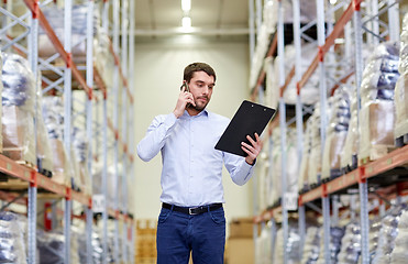 Image showing man with clipboard and smartphone at warehouse