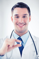 Image showing young male doctor offering pill