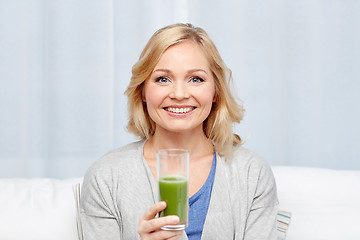 Image showing happy woman drinking green juice or shake at home