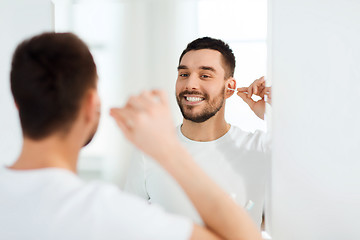 Image showing man cleaning ear with cotton swab at bathroom