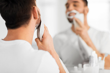 Image showing close up of man removing shaving foam from face