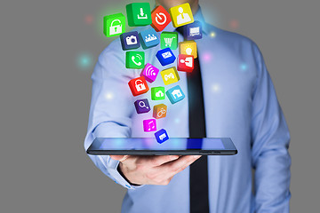 Image showing Businessman holding a tablet pc with mobile applications icons on virtual screen . Internet and business concept.