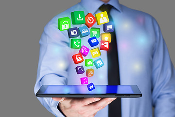 Image showing Businessman holding a tablet pc with mobile applications icons on virtual screen . Internet and business concept.