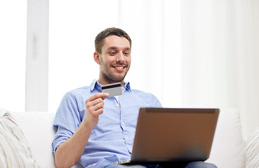 Image showing smiling man with laptop and credit card at home