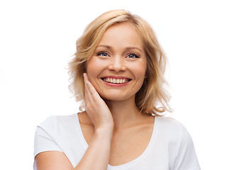 Image showing smiling woman in white t-shirt touching her face