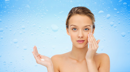 Image showing young woman applying cream to her face