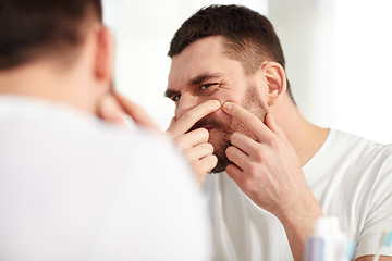 Image showing man squeezing pimple at bathroom mirror