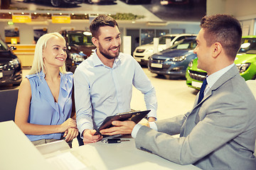 Image showing happy couple with car dealer in auto show or salon