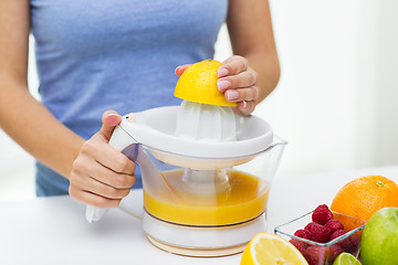 Image showing close up of woman squeezing fruit juice at home