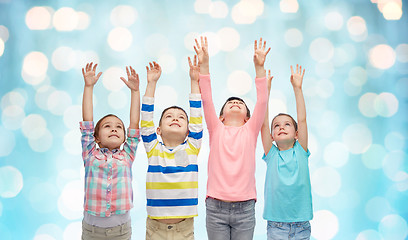 Image showing happy children with raised hands over blue lights