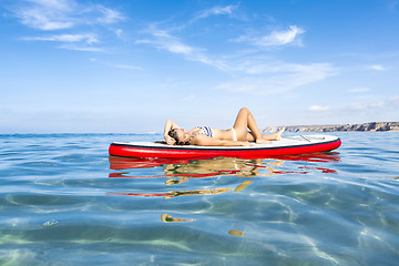 Image showing Woman relaxing over a paddle surfboard