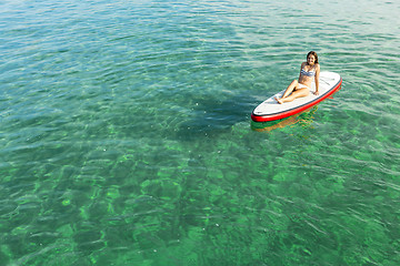 Image showing Woman relaxing over a paddle surfboard