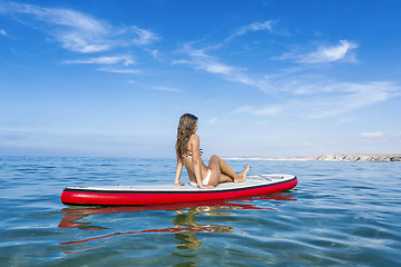 Image showing Woman sitting over a paddle surfboard