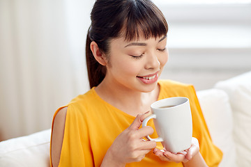 Image showing happy asian woman drinking from tea cup