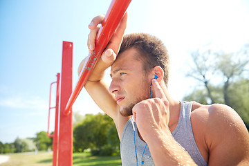 Image showing young man with earphones and horizontal bar