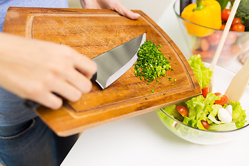 Image showing close up of woman with chopped onion cooking salad