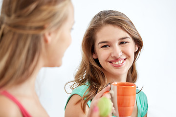 Image showing happy young women drinking tea with sweets at home