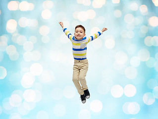 Image showing happy little boy jumping in air over blue lights