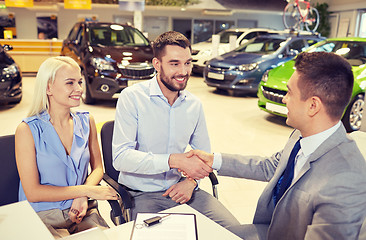 Image showing happy couple with car dealer in auto show or salon