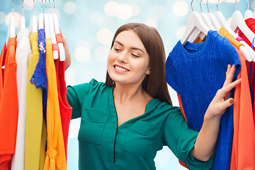 Image showing happy woman choosing clothes at wardrobe