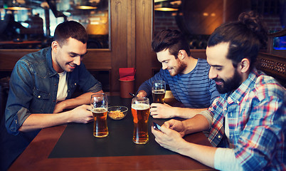 Image showing male friends with smartphones drinking beer at bar