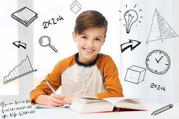 Image showing smiling student boy writing to notebook at home