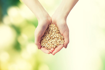 Image showing close up of woman hands holding oatmeal flakes