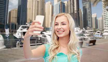 Image showing smiling young woman taking selfie with smartphone