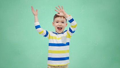 Image showing happy boy waving hands over green school board