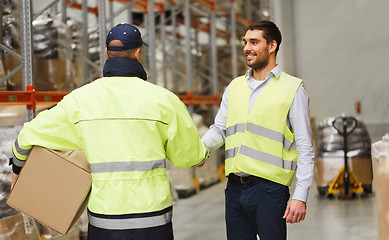 Image showing men in safety vests shaking hands at warehouse