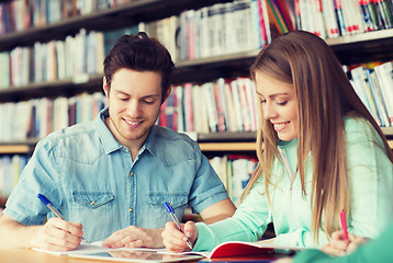 Image showing happy students writing to notebooks in library