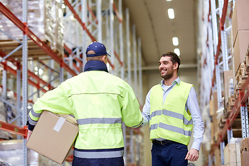 Image showing men in safety vests shaking hands at warehouse