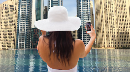 Image showing woman taking selfie with smartphone over city pool