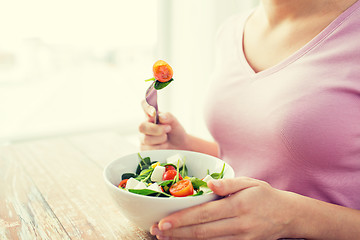 Image showing close up of young woman eating salad at home