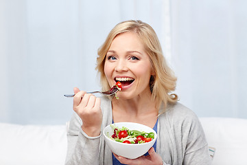 Image showing smiling middle aged woman eating salad at home