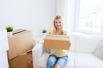 Image showing smiling young woman with cardboard box at home