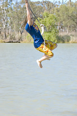 Image showing girl swinging over river