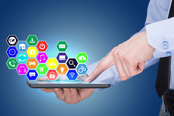 Image showing Businessman holding a tablet pc with mobile applications icons on virtual screen . Internet and business concept.