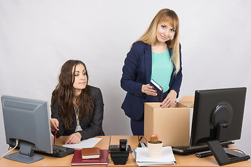 Image showing An employee in the office watching colleague who happily collects things