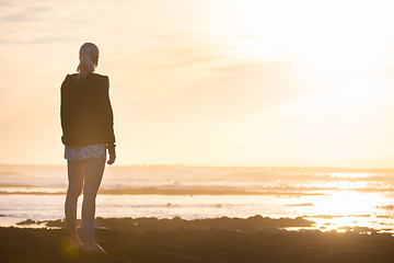 Image showing Woman on sandy beach watching sunset.