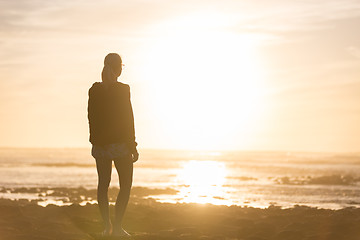 Image showing Woman on sandy beach watching sunset.