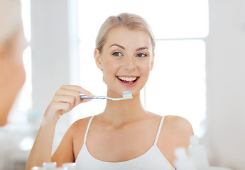 Image showing woman with toothbrush cleaning teeth at bathroom