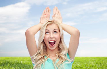 Image showing happy smiling young woman making bunny ears