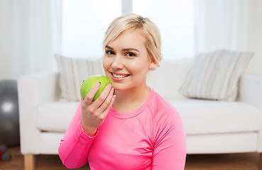 Image showing happy woman eating apple at home