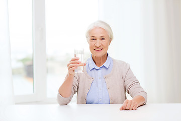 Image showing happy senior woman with glass of water at home