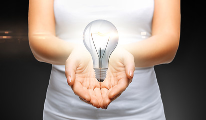 Image showing close up of womans cupped hands with light bulb