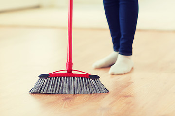 Image showing close up of woman legs with broom sweeping floor