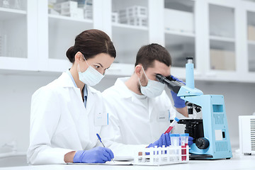 Image showing scientists with clipboard and microscope in lab