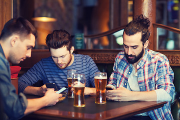 Image showing male friends with smartphones drinking beer at bar